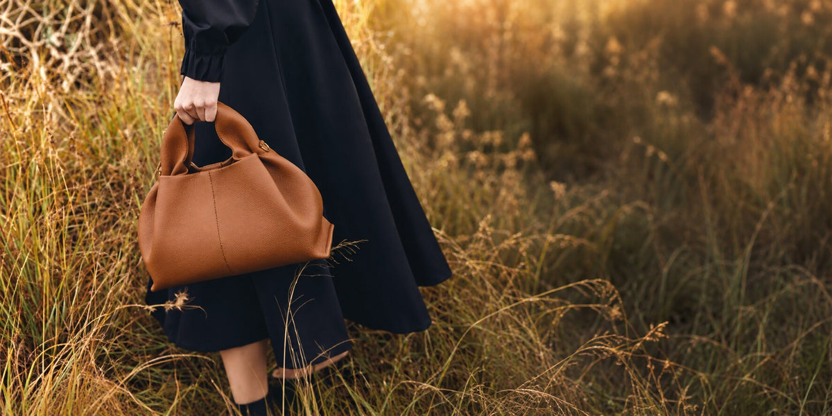 Cognac sculpted handbag carried in a sunlit meadow